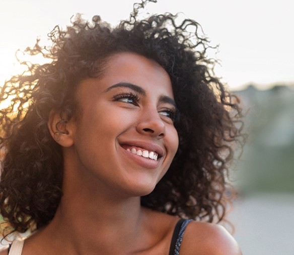 Woman with curly hair smiling outside