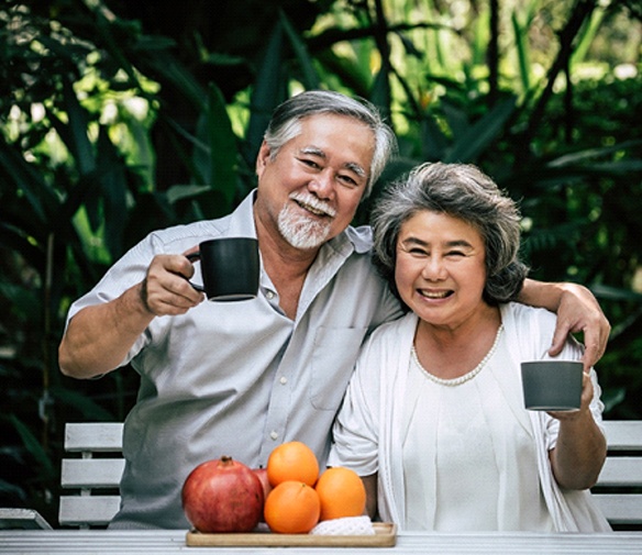 An older couple sitting outside enjoying coffee and fruit together