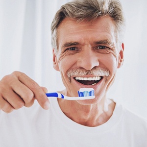 man brushing his teeth because he prioritizes oral hygiene