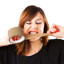 Woman using teeth to cut tape