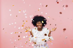 smiling woman who has made New Year’s resolutions with confetti 